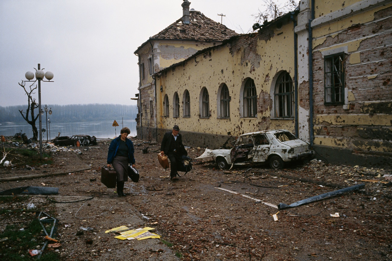 A middle-aged Croatian couple flees the ruined city of Vukovar past bombed buildings riddled with bullet holes and streets filled with rubble after a three-month battle between the Croatian armed forces and the Yugoslavian Federal Army in Vukovar. The Yugoslavian Federal Army completely destroyed the Croatian city and killed thousands of civilians., Image: 16127894, License: Rights-managed, Restrictions: Content available for editorial use, pre-approval required for all other uses. This content may not be materially modified or used in composite content., Model Release: no, Credit line: Profimedia, Corbis