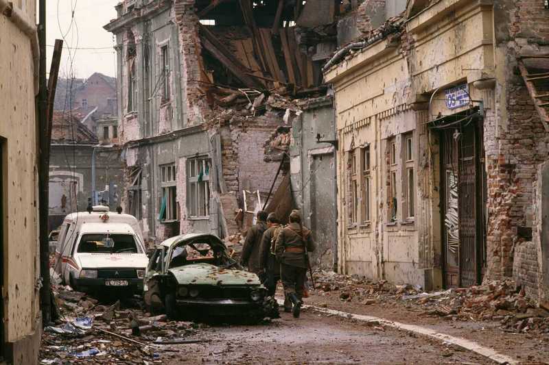 Yugoslavian soldiers and Serb paramilitaries, including Zeljko "Arkan" Raznatovic, walk past bombed buildings riddled with bullet holes and streets filled with rubble after a three-month battle between the Croatian armed forces and the Yugoslavian Federal Army in Vukovar. The Yugoslavian Federal Army completely destroyed the Croatian city, killing thousands of civilians, while the Serbian Volunteer Guard, formed by Raznatovic, was responsible for massive ethnic cleansing campaigns against Bosnian Croats., Image: 15114608, License: Rights-managed, Restrictions: Content available for editorial use, pre-approval required for all other uses. This content may not be materially modified or used in composite content., Model Release: no, Credit line: Profimedia, Corbis